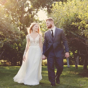 Bride and groom in an apple orchid on their wedding day. The bride is wearing our Serafina earrings.