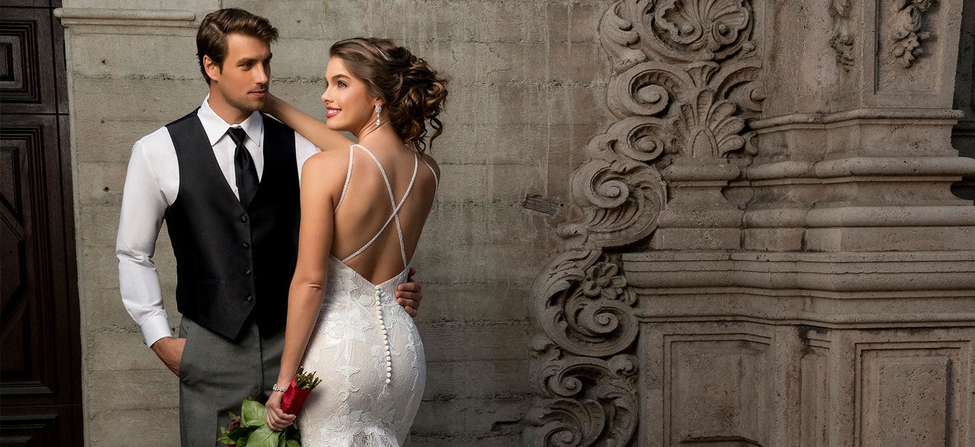 Bride and Groom embraced against a gray stone wall. Bride is wearing Anna Bellagio Bridal jewelry and Hair Accessories.